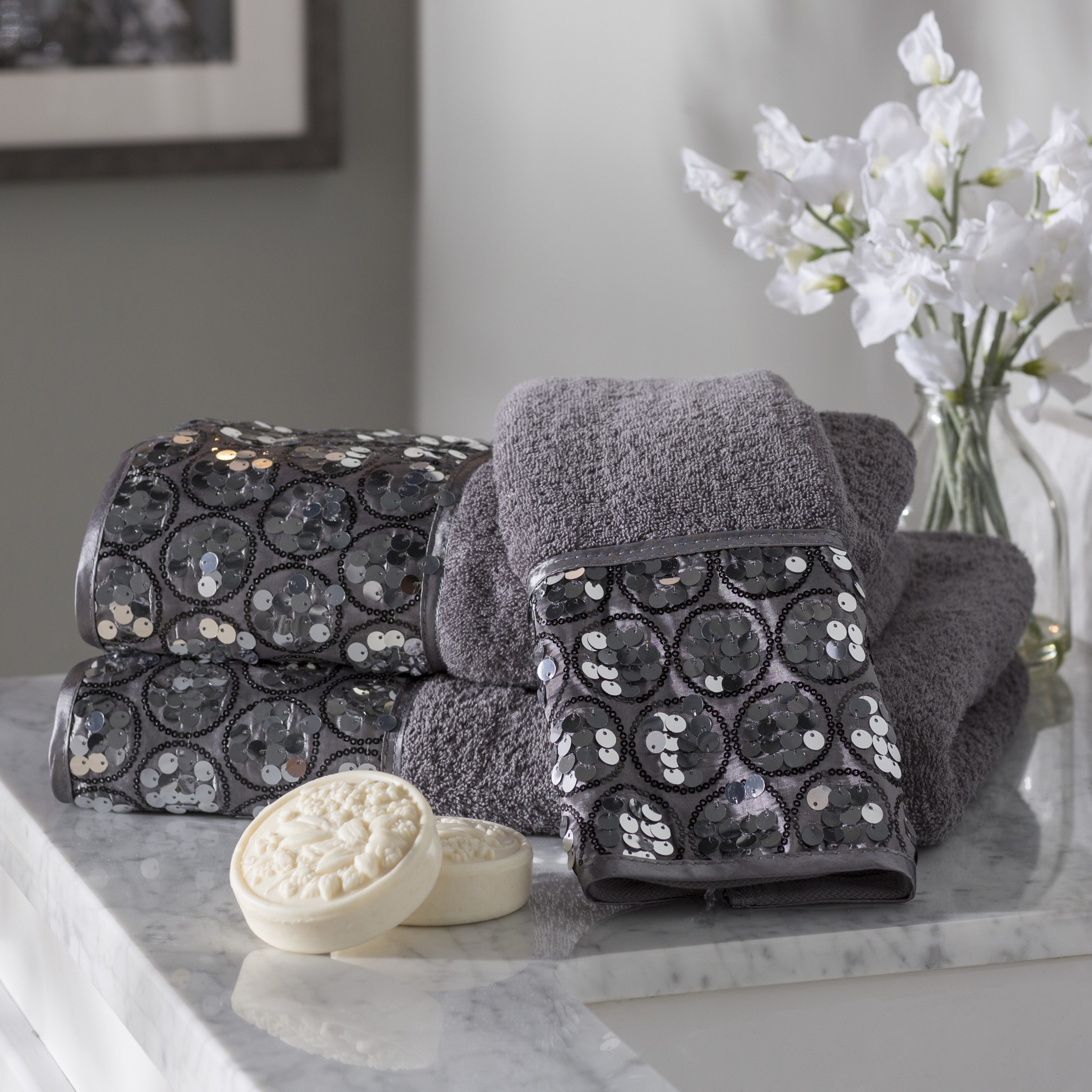 Gray towels with shimmering sequins on a marble-tiled counter