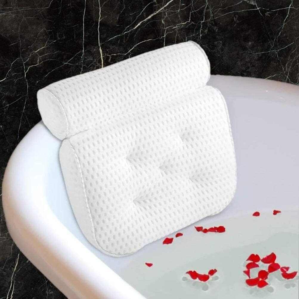 A white contoured bath pillow in a sudsy bathtub filled with candles