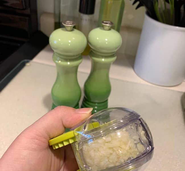 reviewer holding chopper filled with chopped garlic