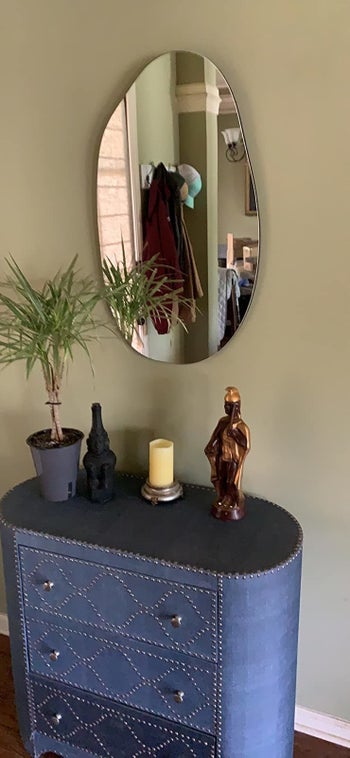 a reviewer photo of the mirror hanging vertically above a dresser