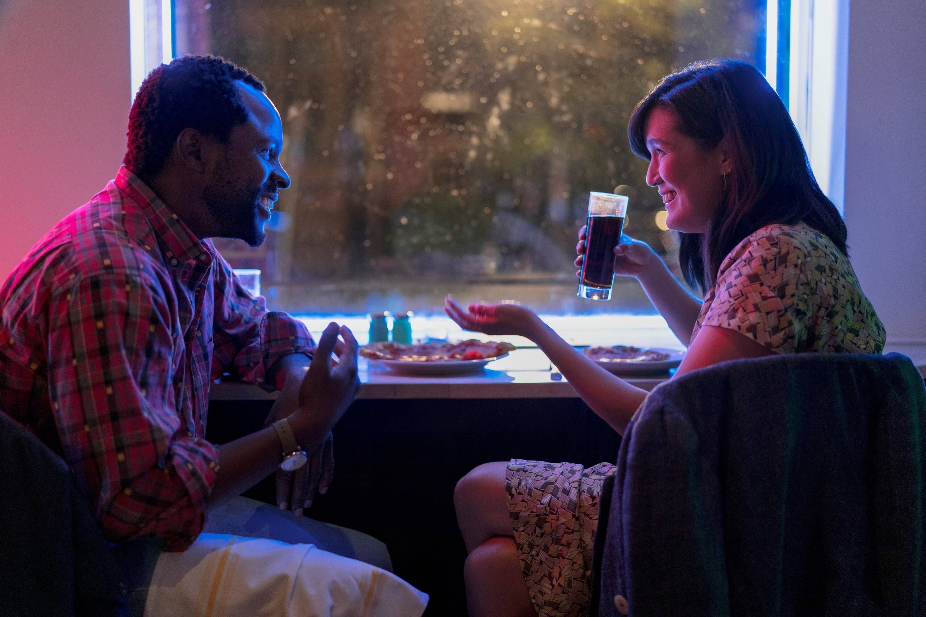 A girl and guy laughing at a table in a diner at night