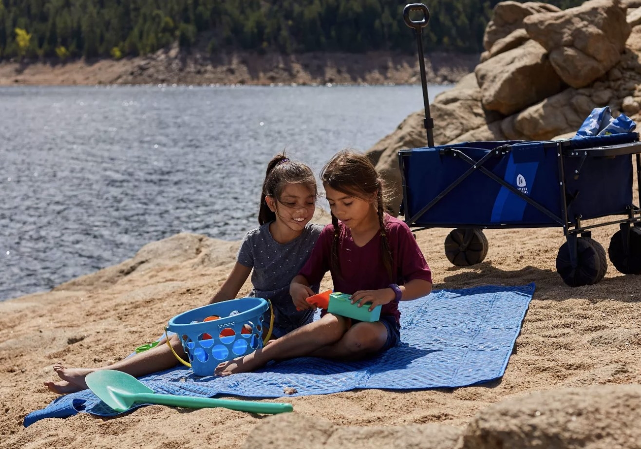 two kids sitting on the blanket on the beach