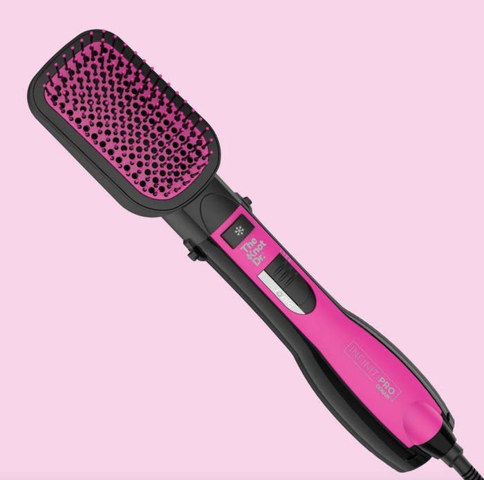 A pink and black heated straightening brush with a paddle design