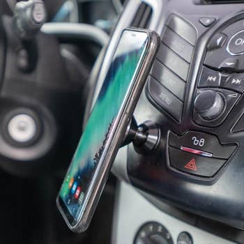 a reviewer photo of a smart phone on the mount in a car 