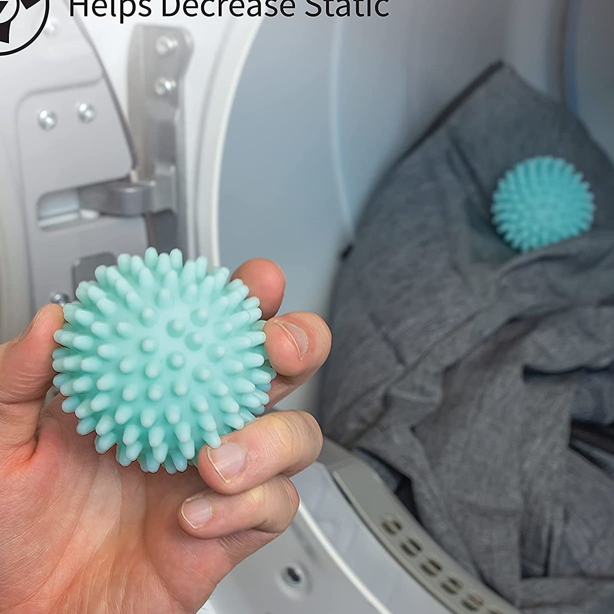 A person holding a dryer ball in front of a dryer