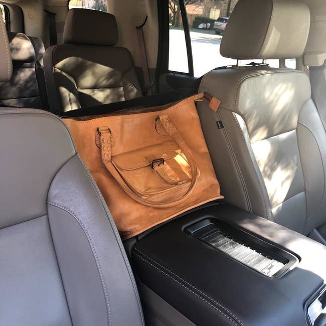 a reviewer photo of their purse being supported by the car cache 
