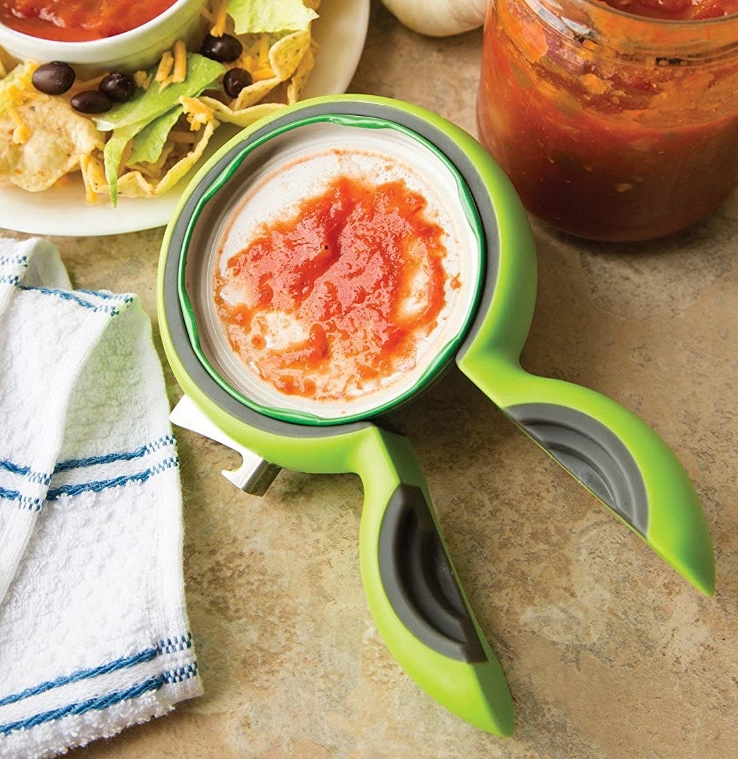 The jar opener around a lid of salsa
