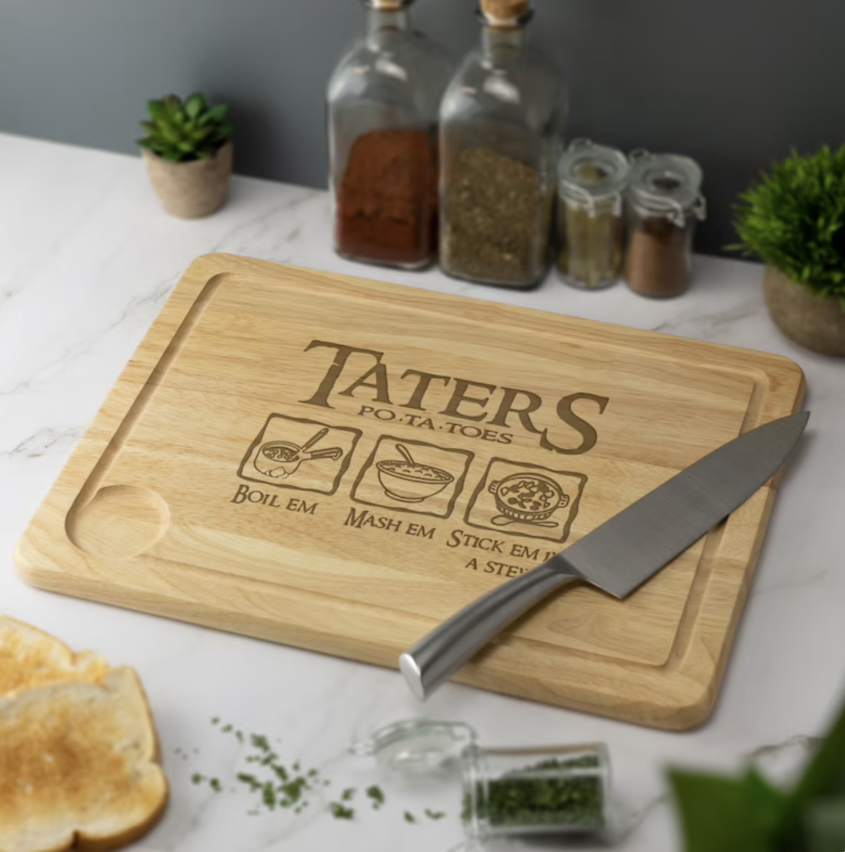 A wooden cutting board with images of boiled, mashed, and stewed potatoes engraved under the word &quot;Taters&quot;
