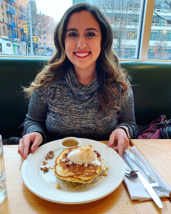 the author with lipstick on while sitting in front of a plate of pancakes