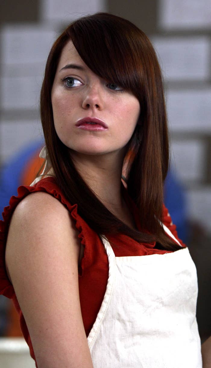 Emma Stone with a swooped bang haircut while wearing an apron in a cooking class