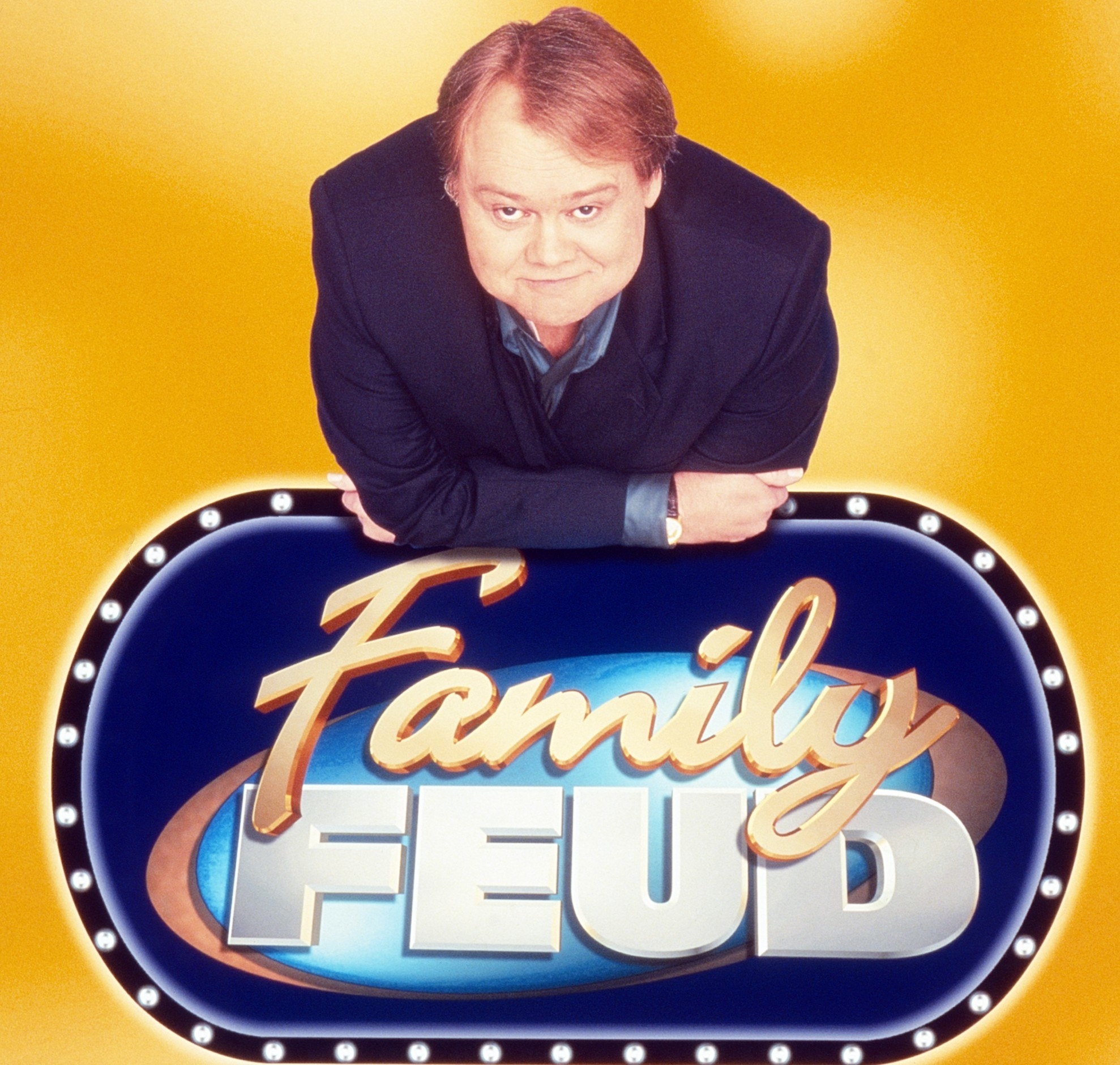 Louie Anderson leaning on a Family Feud logo