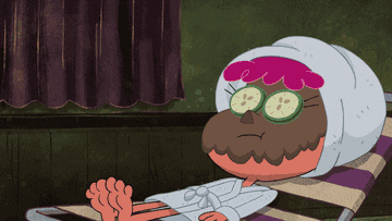 Harvey Beaks laying in a white robe with a brown mud mask on lifting a cucumber off his eye