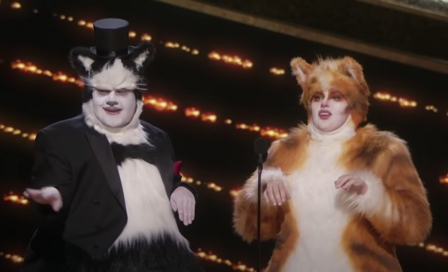 Rebel and James dress up as humanoid cats, complete with face makeup