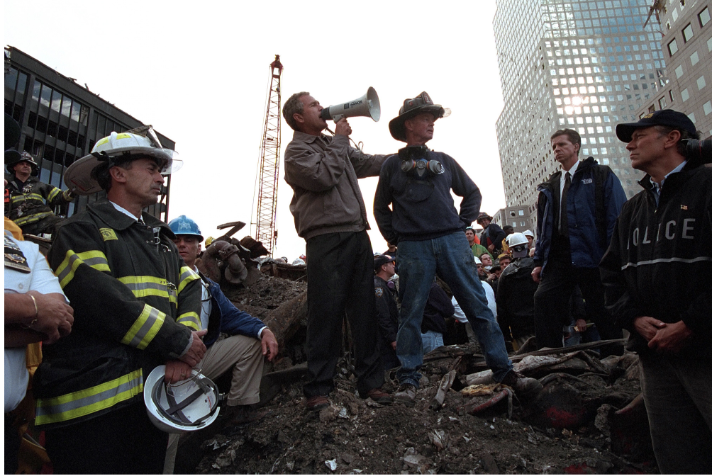 President George W. Bush stands on the wreckage of the World Trade Center with a bullhorn speaking to rescue workers