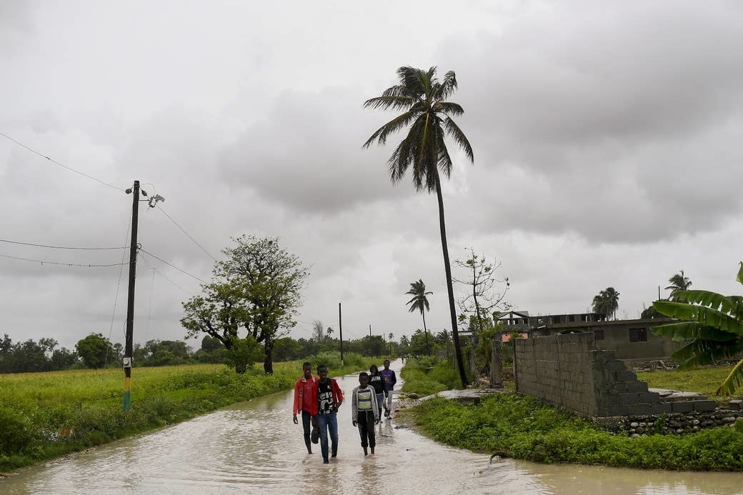 Residents of Haiti wade through a flooded road 