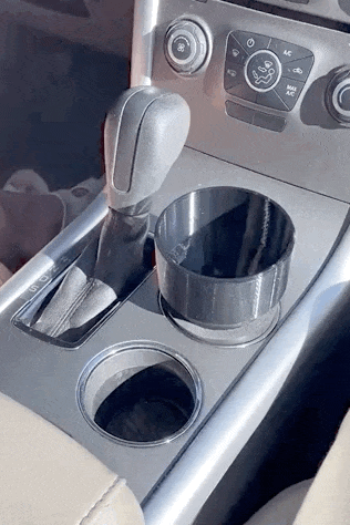 a gif of someone trying to put a hydroflask water bottle in a regular cup holder and then placing it successfully in the bottle cup holder adaptor 
