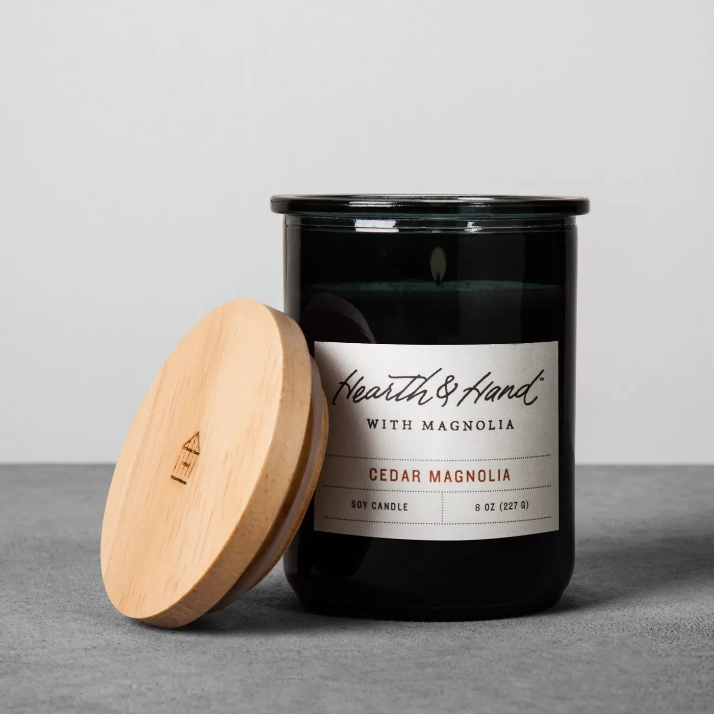 The black candle says &quot;Hearth &amp;amp; Hand&quot; in a script font and has &quot;WITH MAGNOLIA&quot; and &quot;CEDAR MAGNOLIA&quot; below in a serif and non-serif font respectively