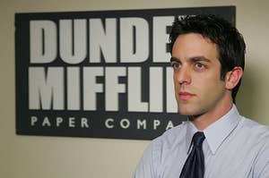 ryan howard standing in front of a dunder mifflin sign