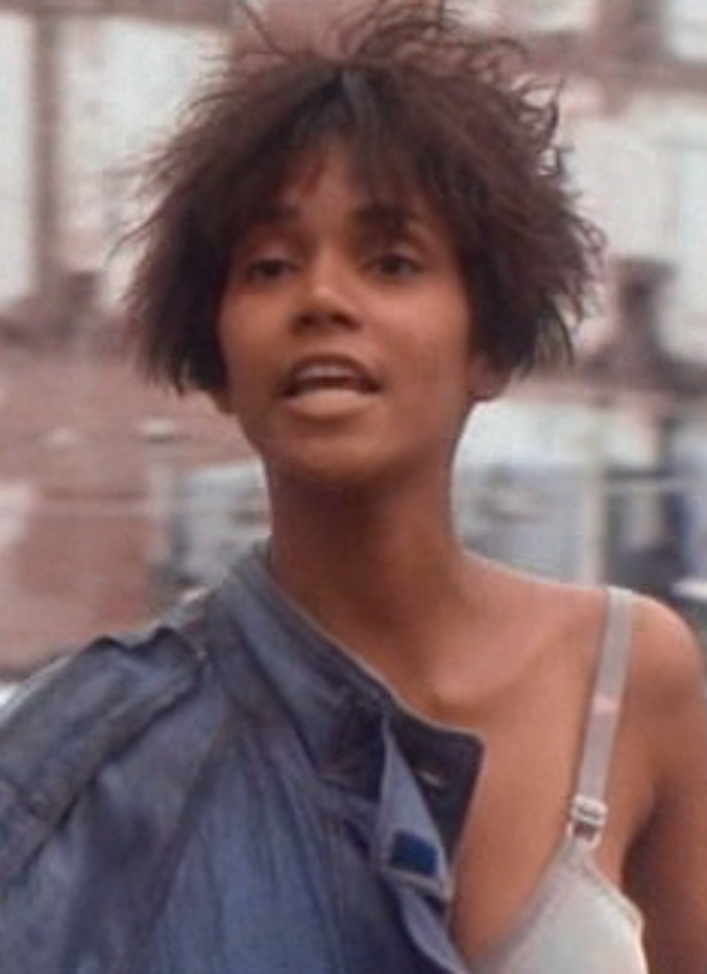 Halle Berry with messy hair while wearing a bra and a jacket on her shoulder