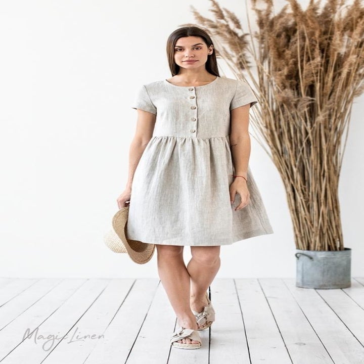 Model in a button down short sleeved light gray linen midi dress
