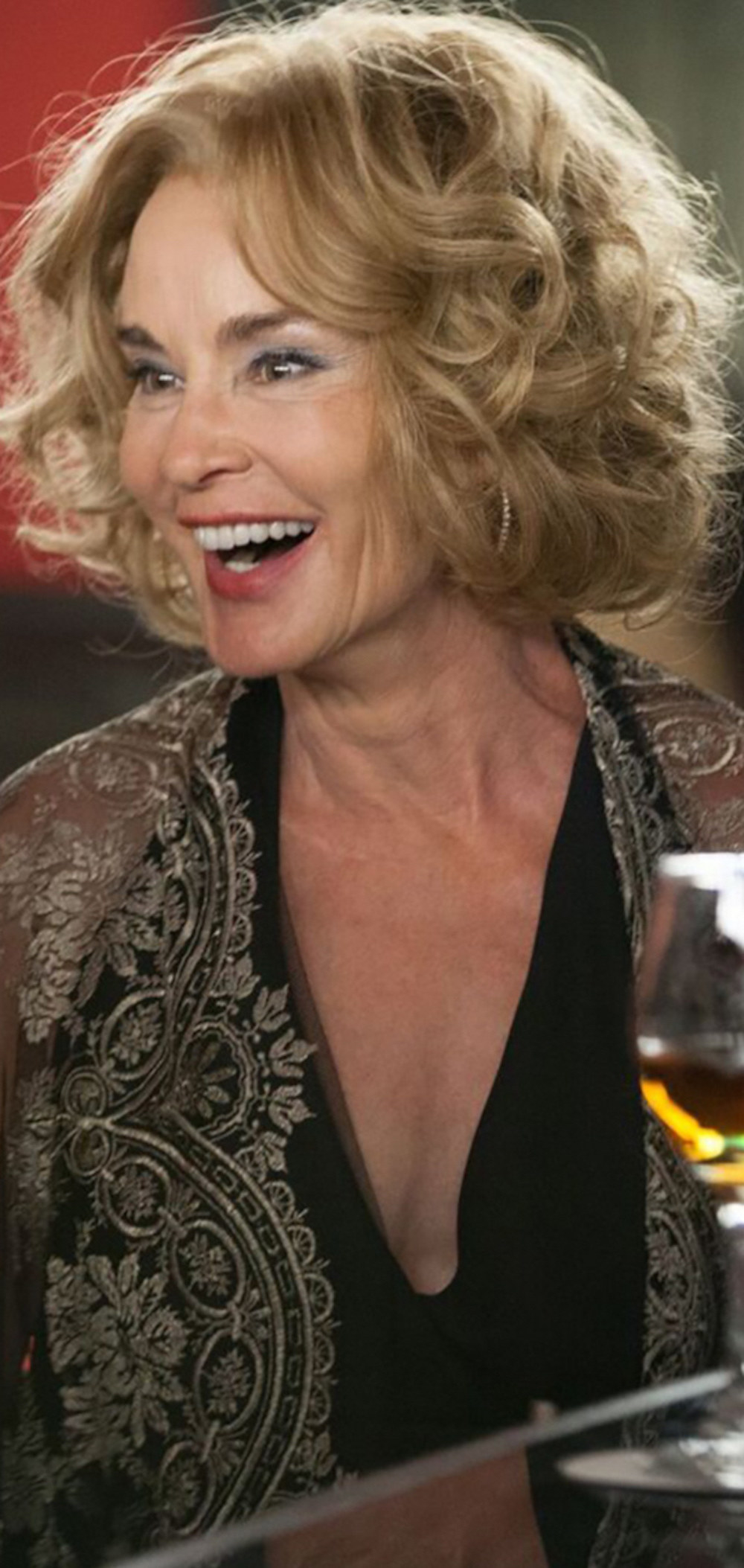 Jessica Lange laughing at a bar while wearing a dress and shawl