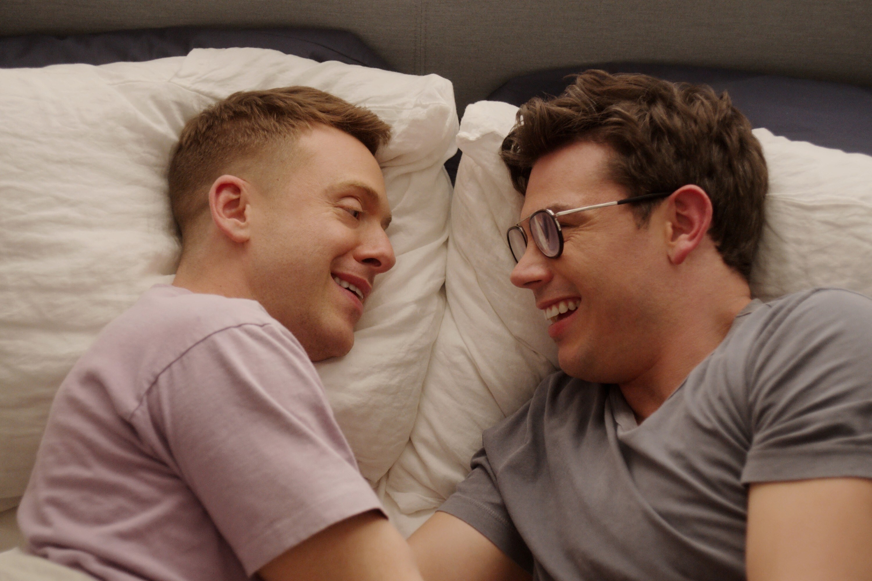 Ryan O&#x27;Connell and Max Jenkins smile at each other in bed