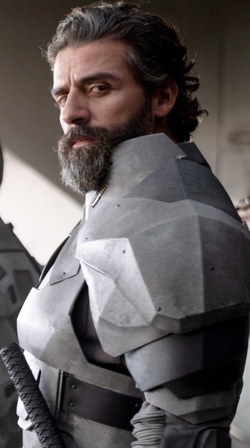 Oscar Isaac with long hair, a long beard, and wearing silver armor