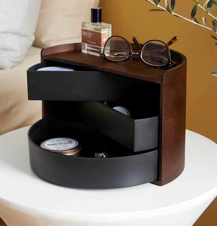 A round jewellery box with three drawers and a shelf on top