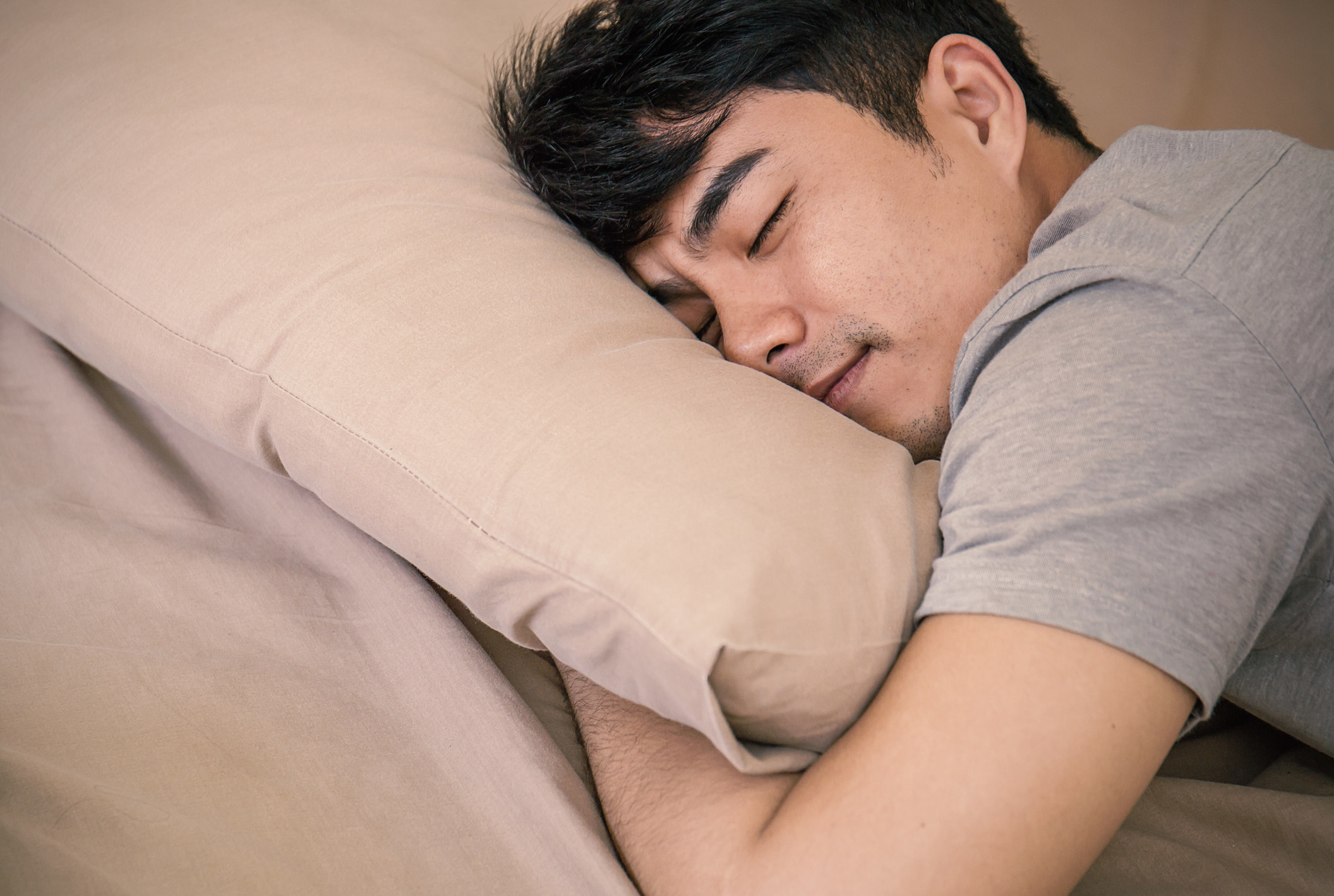 Person holds their pillow while sleeping