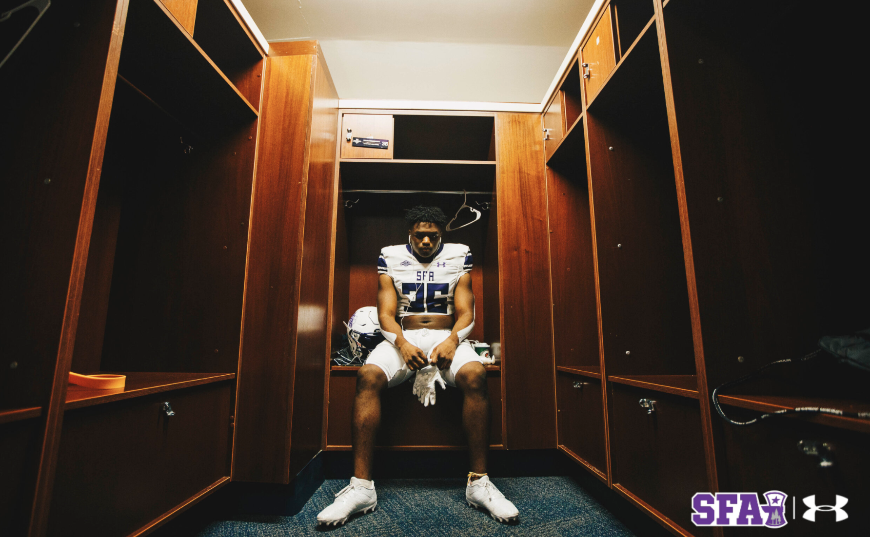 A football player sits alone in an empty locker room