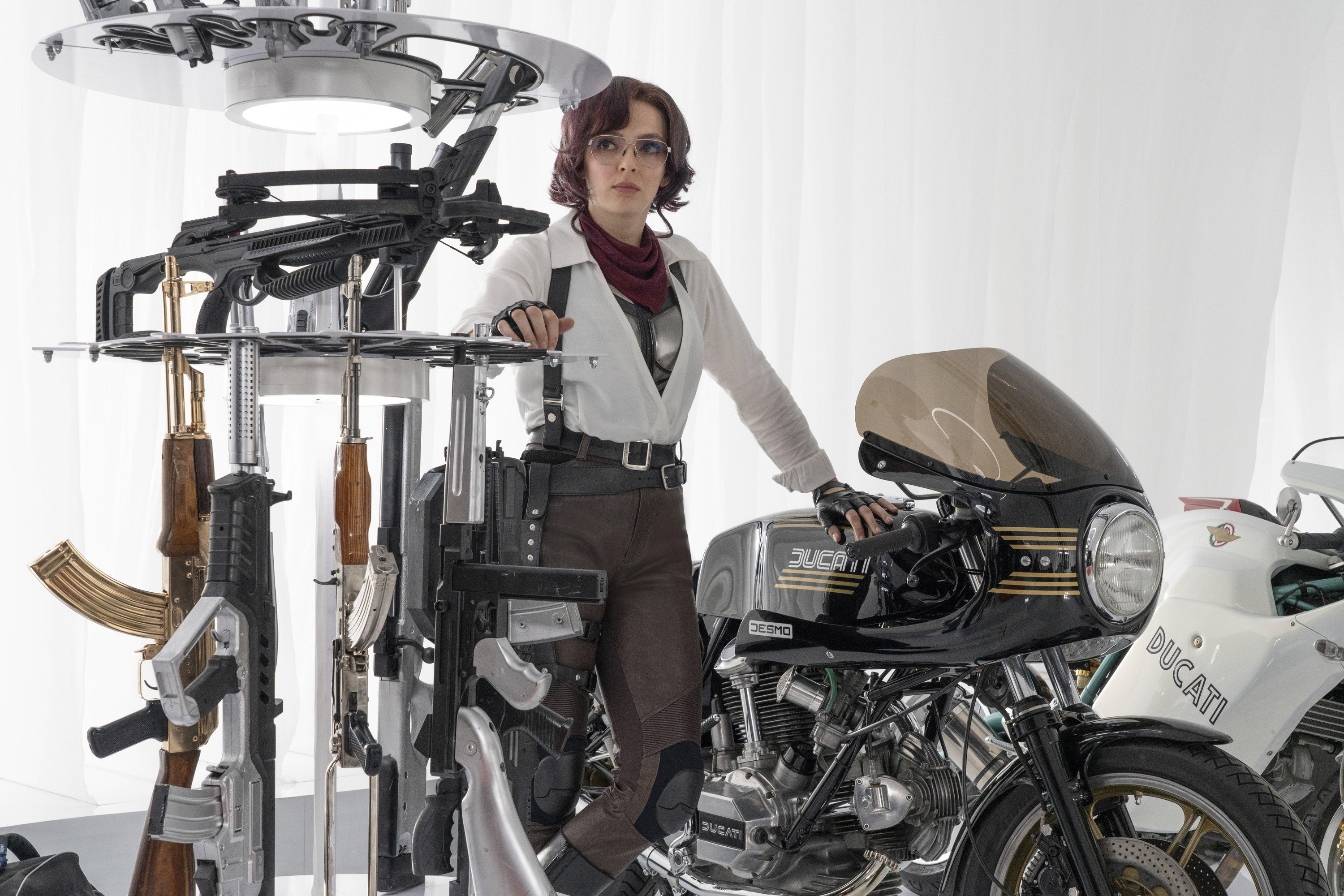 A woman standing in a room full of guns and motorcycles.