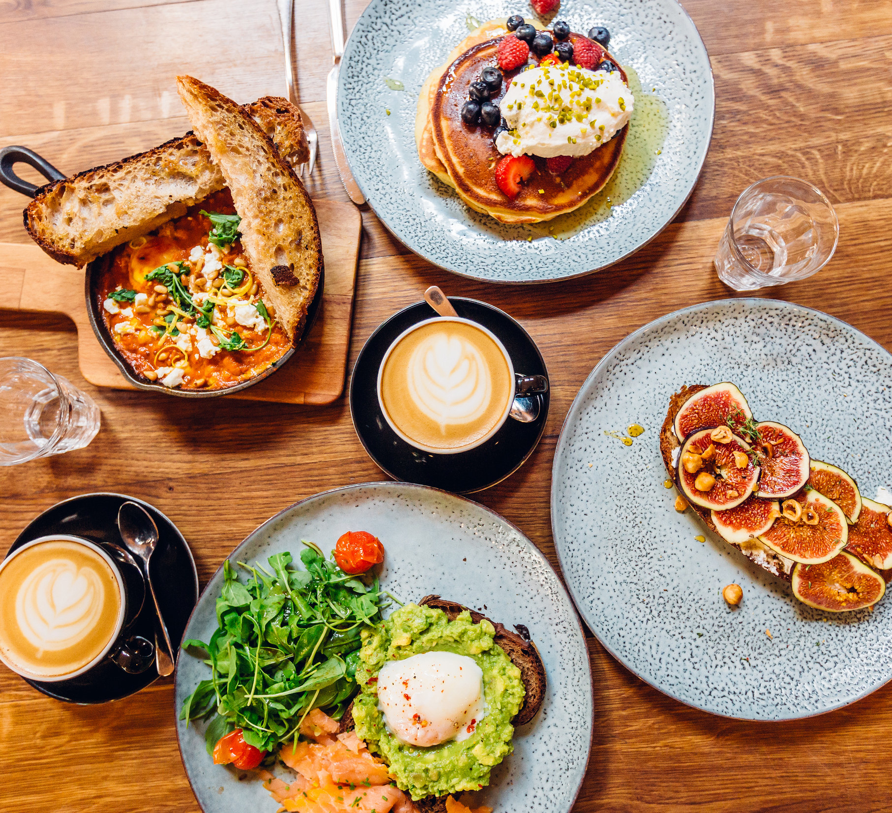 A brunch spread with lattes and a stack of pancakes.