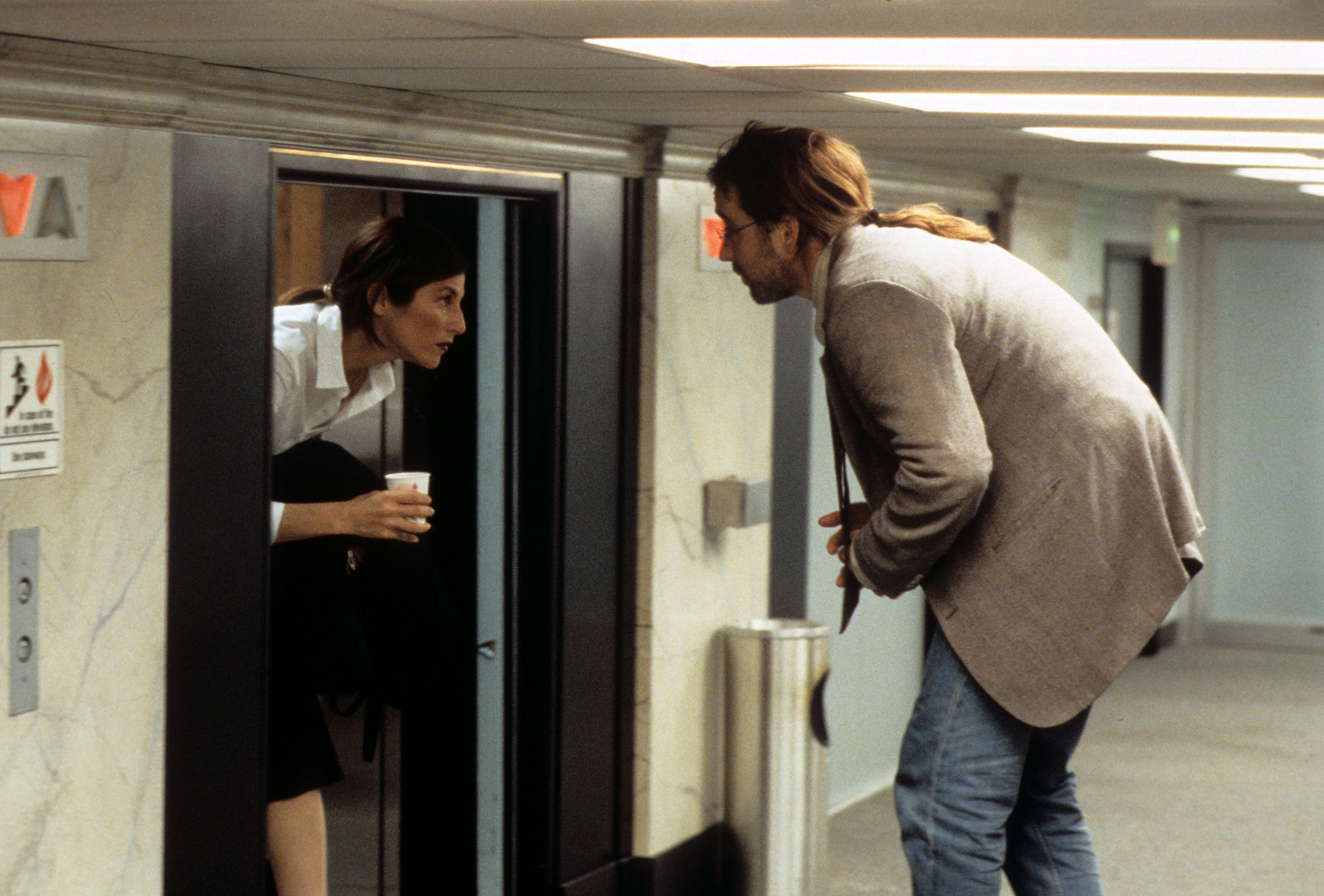 Catherine Keener talking to John Cusack while walking out of an elevator