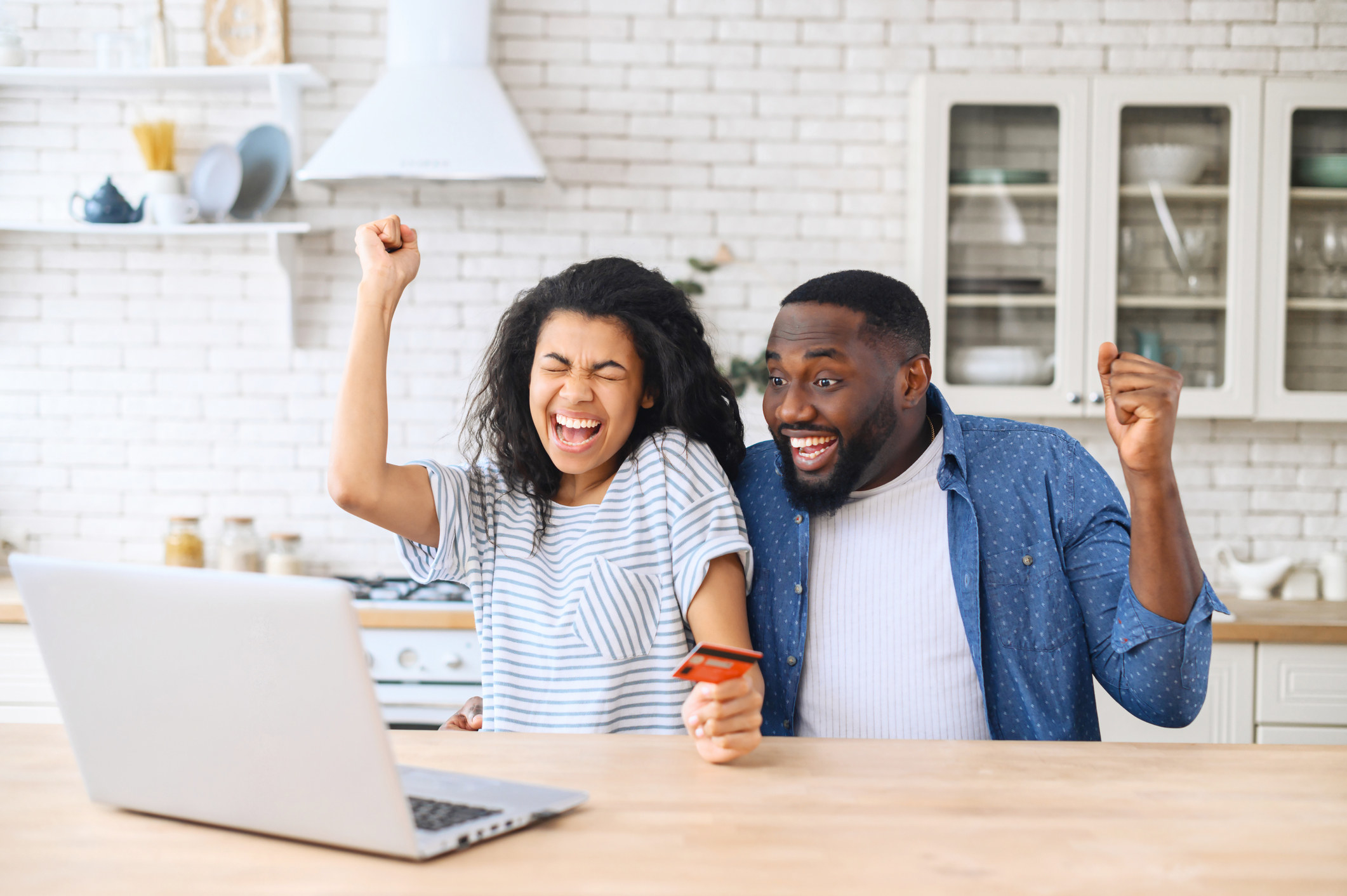 A couple looking at a laptop and celebrating