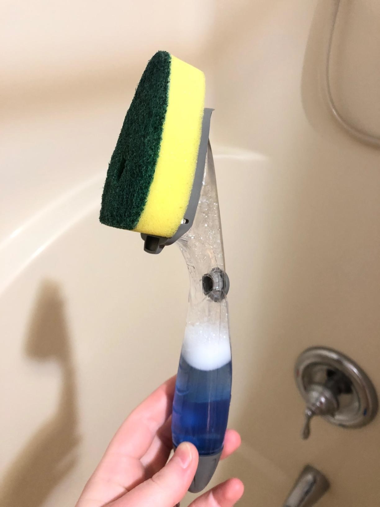 Reviewer holding dishwashing wand filled with vinegar and dish soap