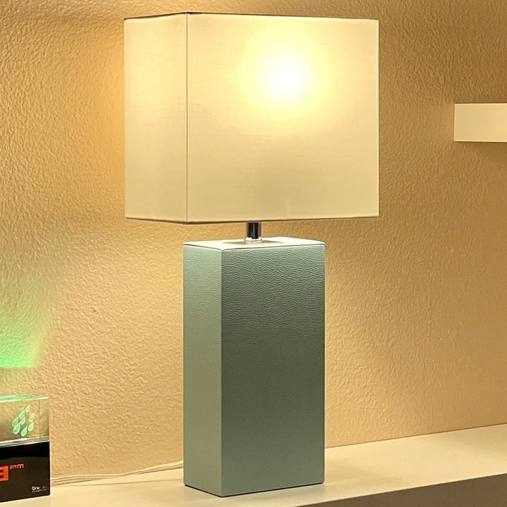a review photo of the lamp in a soft blue turned on to illustrate brightness