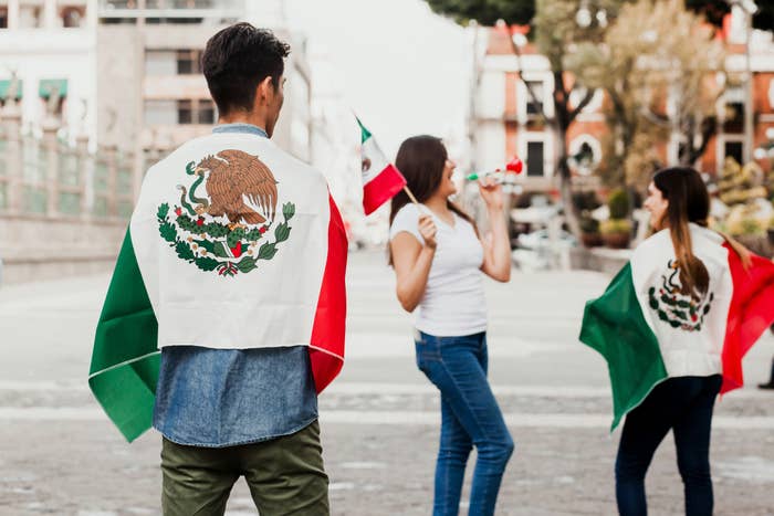 three people holding mexican flags