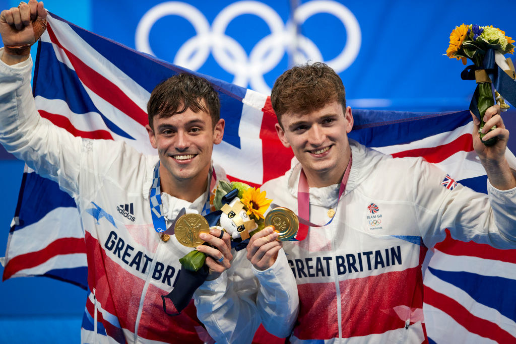 Tom Daley and his teammate Matty Lee holding up their Olympic gold medals and smiling