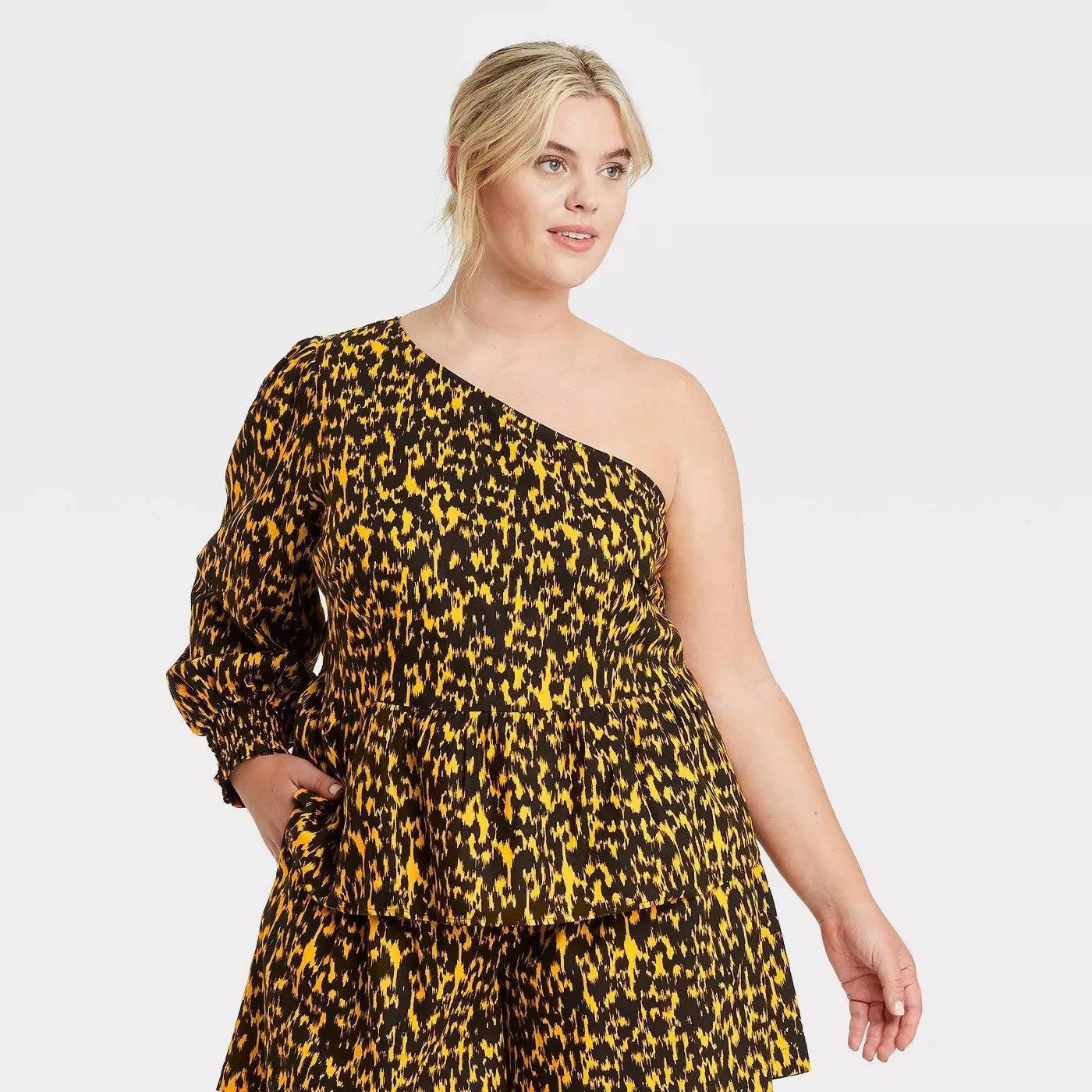 Model wearing black and yellow spotted top with cuffed sleeve