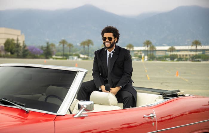 The Weeknd is photographed smiling inside a convertible
