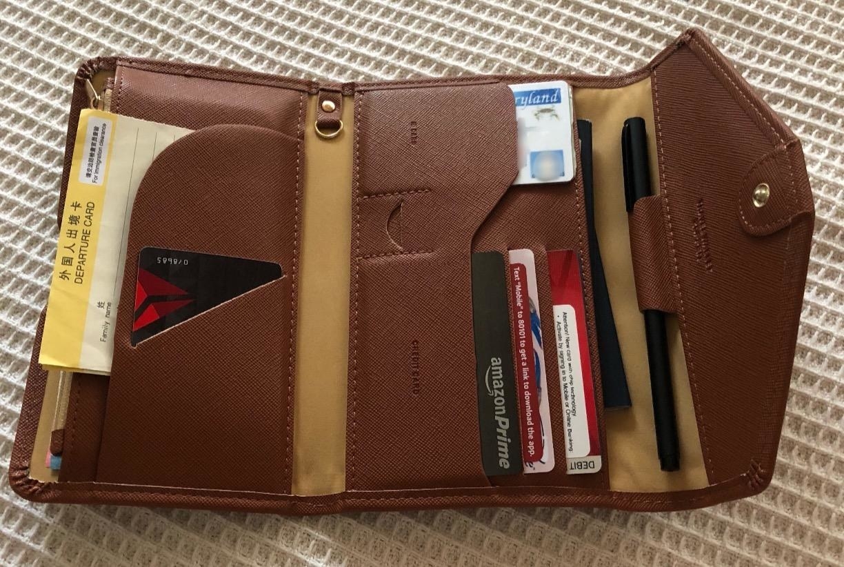 image of reviewer&#x27;s seal brown foldable wallet filled with credit cards, travel socuments, and a pen