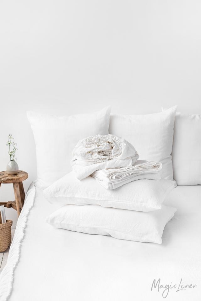 the white linen sheet set folded on top of a bed dressed with the white linen sheet set
