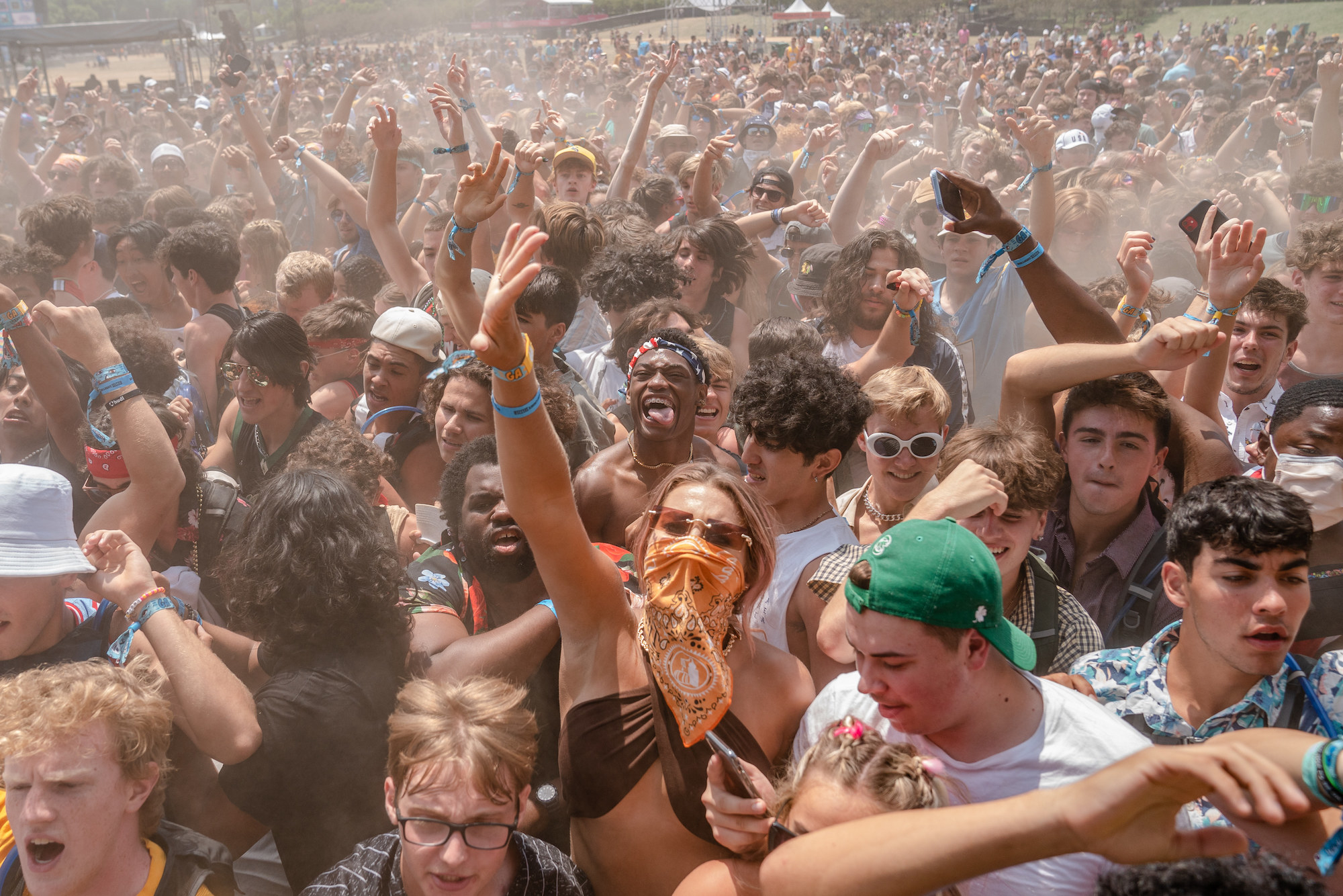Dust fills the air as attendees lift their arms up at Lollapalooza music festival.