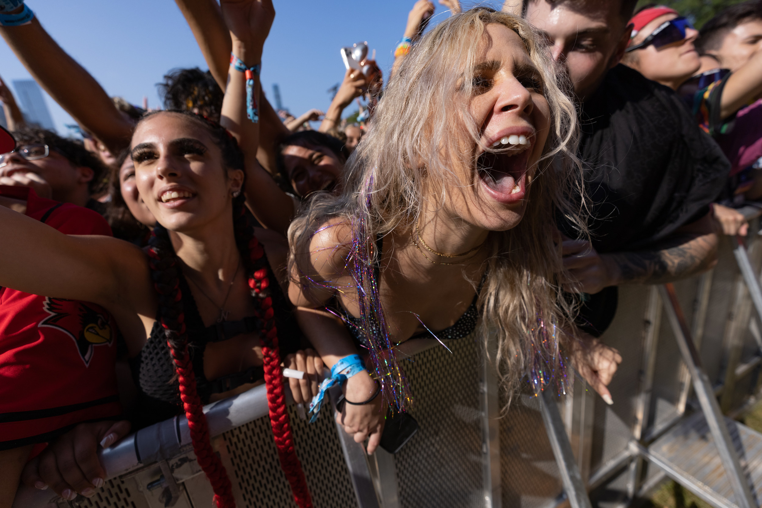 Young audience members at Lollapalooza music festival raise hands and scream in excitement at the music festival in Chicago.