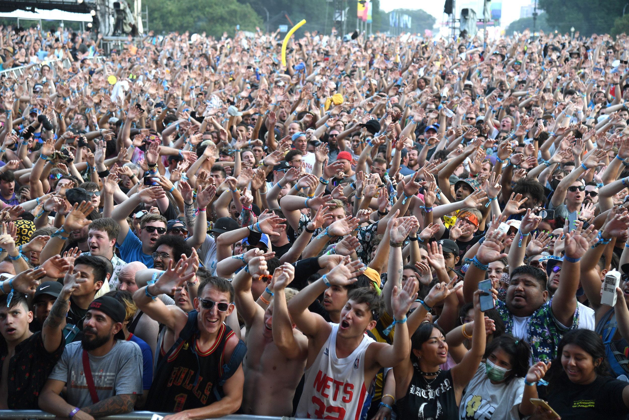 Hundreds of fans raise hands in the air and sing during an afternoon at Lollapalooza music festival.