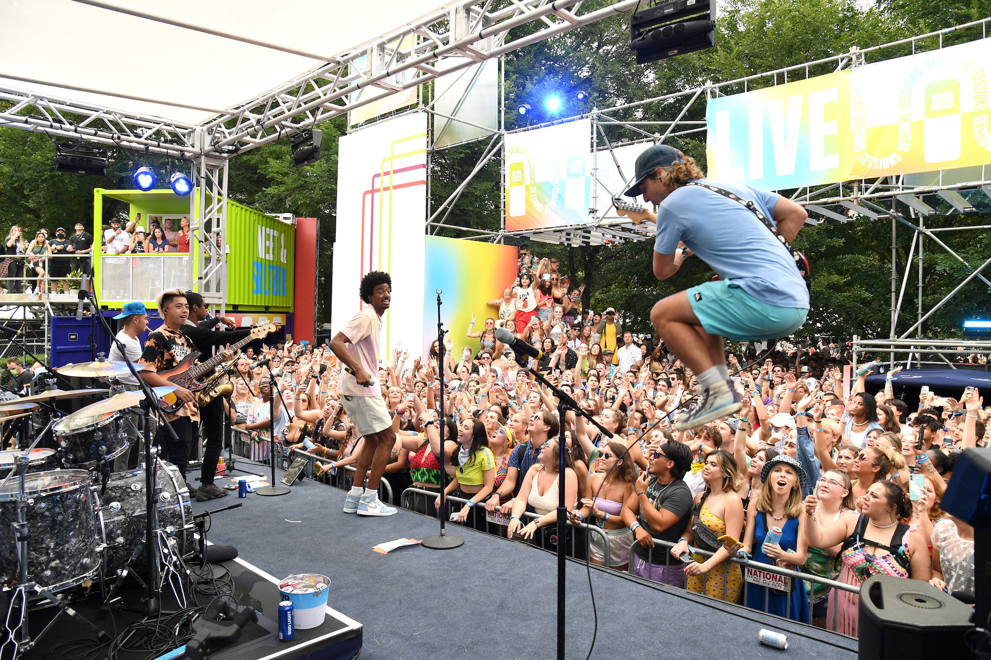 A musician is seen jumping high in the air with a guitar as an audience takes in a performance at Lollapalooza. 