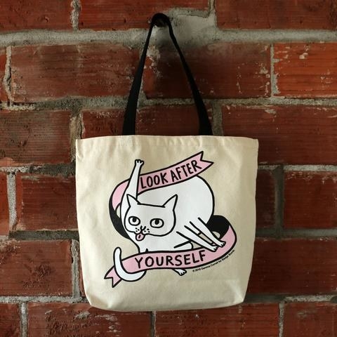 the look after yourself tote featuring a white cat licking their butt