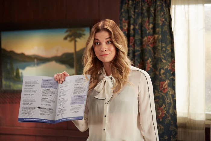 Annie Murphy as Alexis Rose holding up a pamphlet