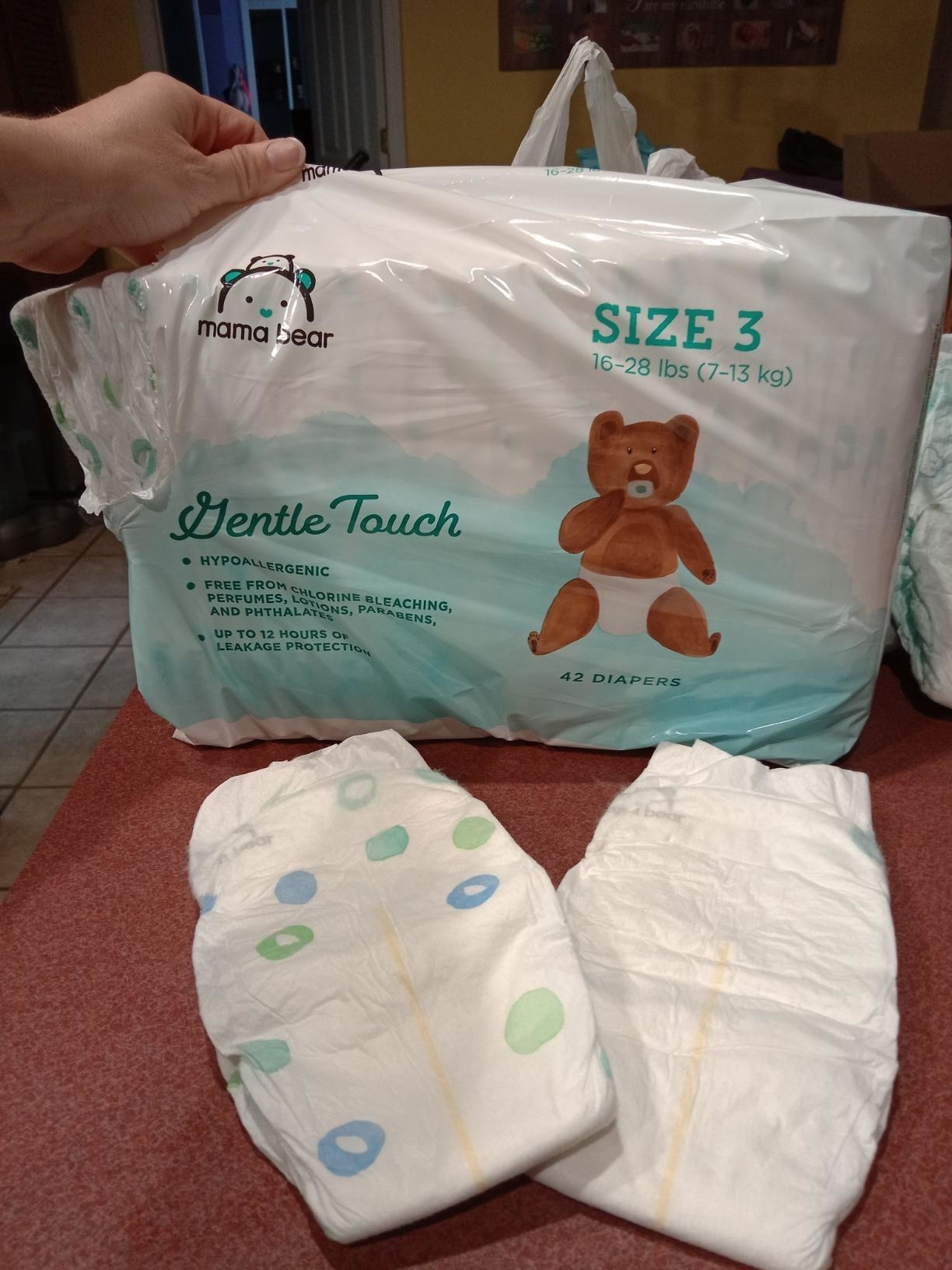 Reviewer holding pamper bag with two pampers on couch