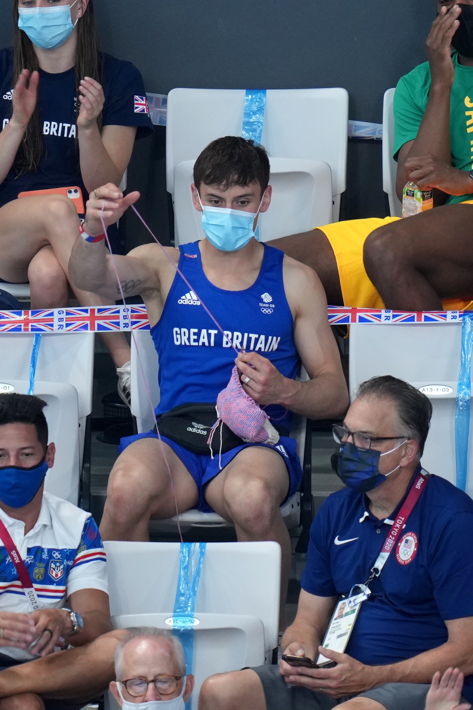 Tom knitting in the stands as he looks at the diving pool